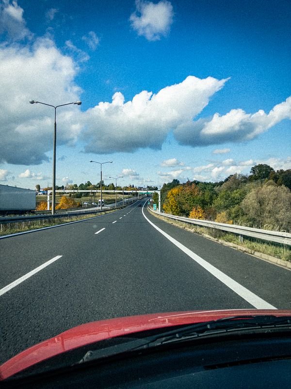 A scenic view of a highway curving through a landscape under a blue sky with clouds.