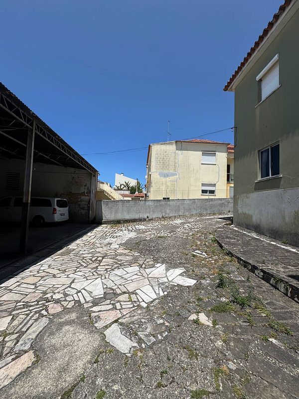 A view of a sloped, uneven pathway leading to a residential area under a clear blue sky.