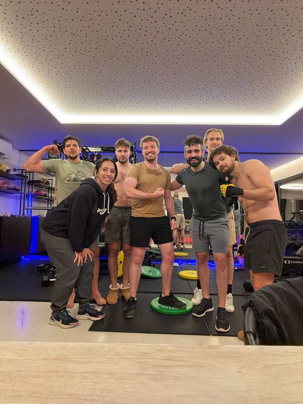 Photo of two men in a gym performing dumbbell exercises beside a cable machine.