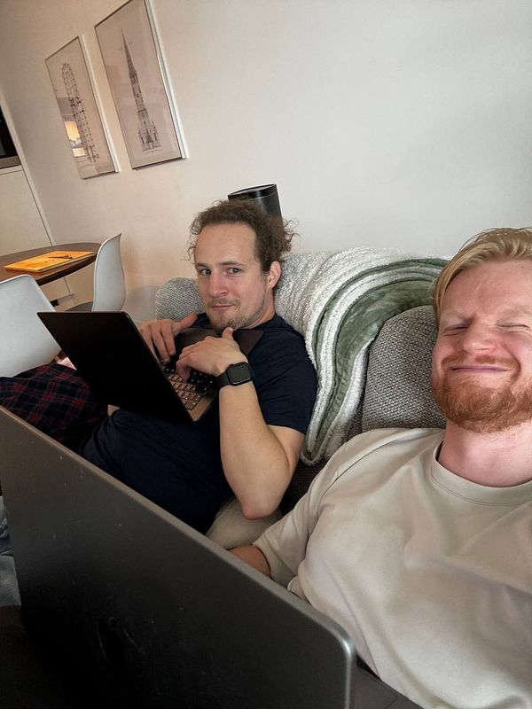 Workspace setup with laptop, notebooks, coffee cup, and stationary on a wooden surface.