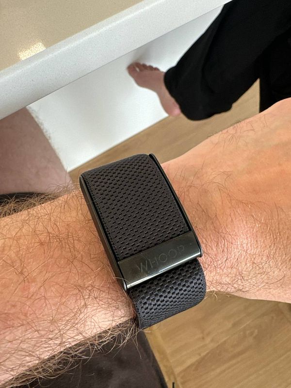 A close-up of a wrist wearing a black Whoop fitness tracker.