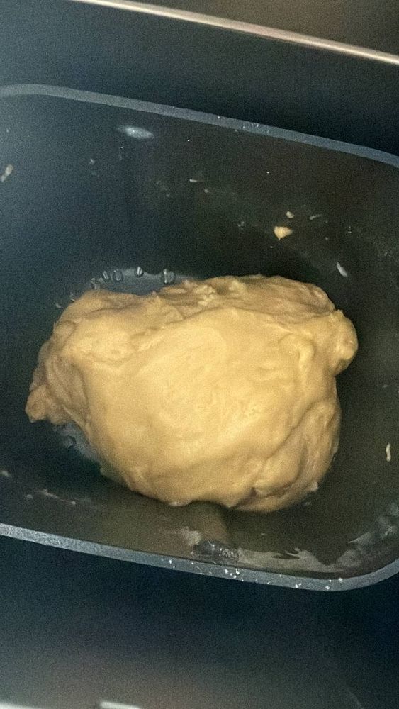 A ball of brioche bread dough inside a bread machine pan.