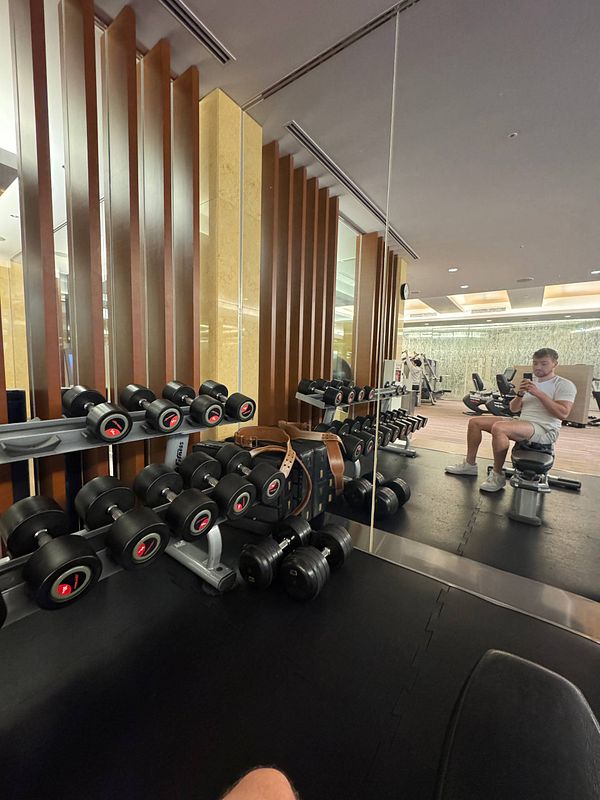 A gym interior featuring dumbbells and a person seated on a bench.