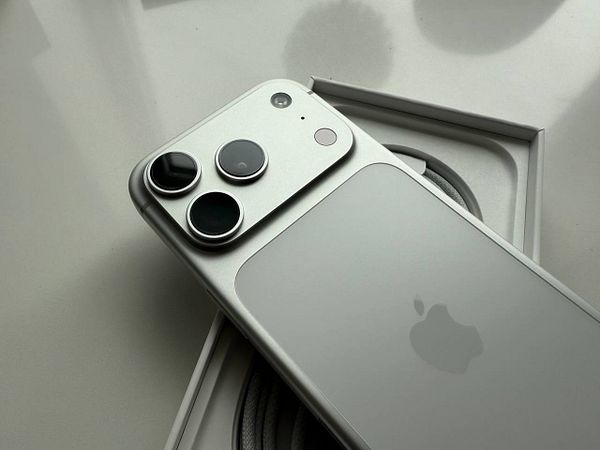 A new iPhone is displayed in its box alongside a charging cable.