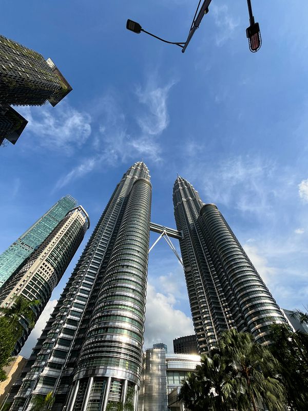 The image captures the iconic Petronas Twin Towers in Kuala Lumpur against a clear blue sky.