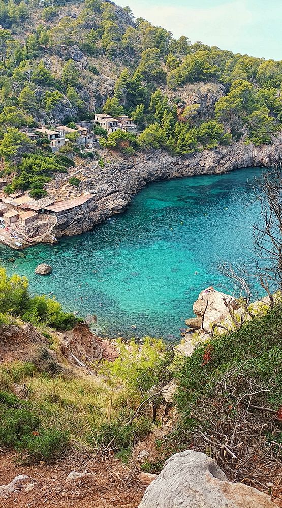 A picturesque coastal scene featuring a serene turquoise bay surrounded by rocky cliffs and lush greenery.