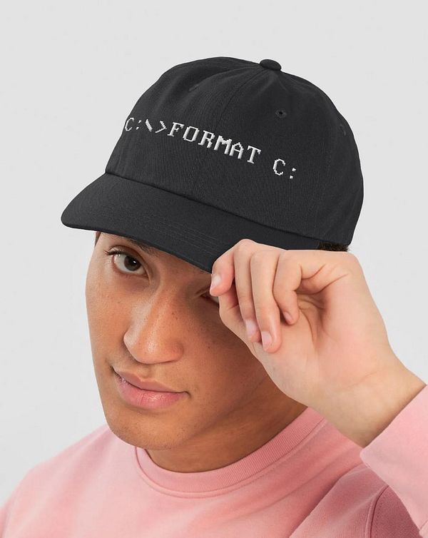 A young man is wearing a black cap with a computer command printed on it.