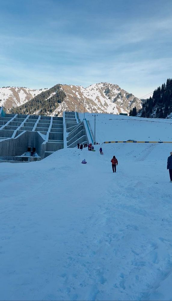 A snowy landscape featuring a family hike with mountains in the background.