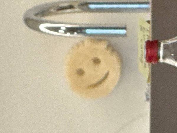 A cheerful smiley face decoration is mounted on a wall near a kitchen faucet.