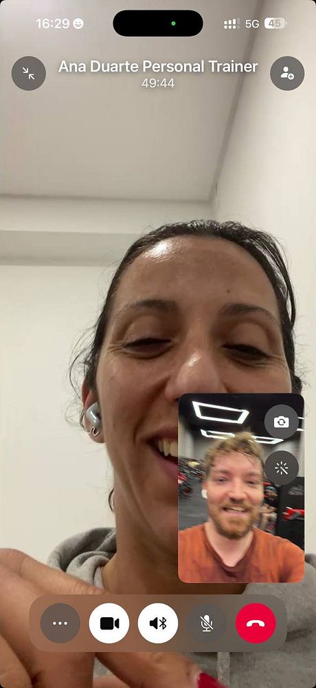 A woman performing a squat exercise in a gym studio with resistance bands under guidance of a personal trainer.