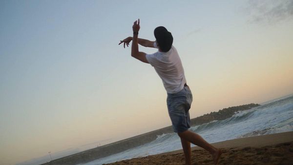 A dancer performs on a beach at sunset, showcasing a dynamic pose.