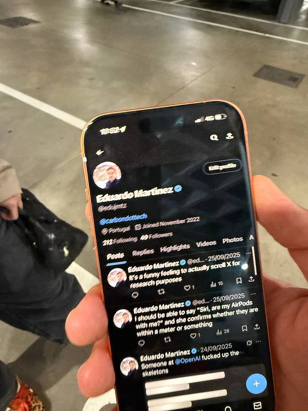 A person is holding a smartphone displaying a Twitter profile of Eduardo Martinez in a supermarket setting.