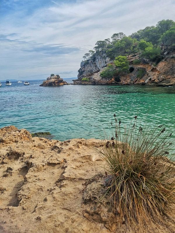 A serene beach scene featuring clear turquoise waters and rocky cliffs.