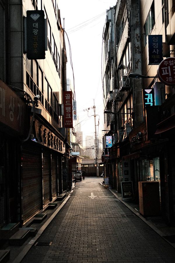 Cozy bedroom setup with open book, glasses, laptop, and natural light.