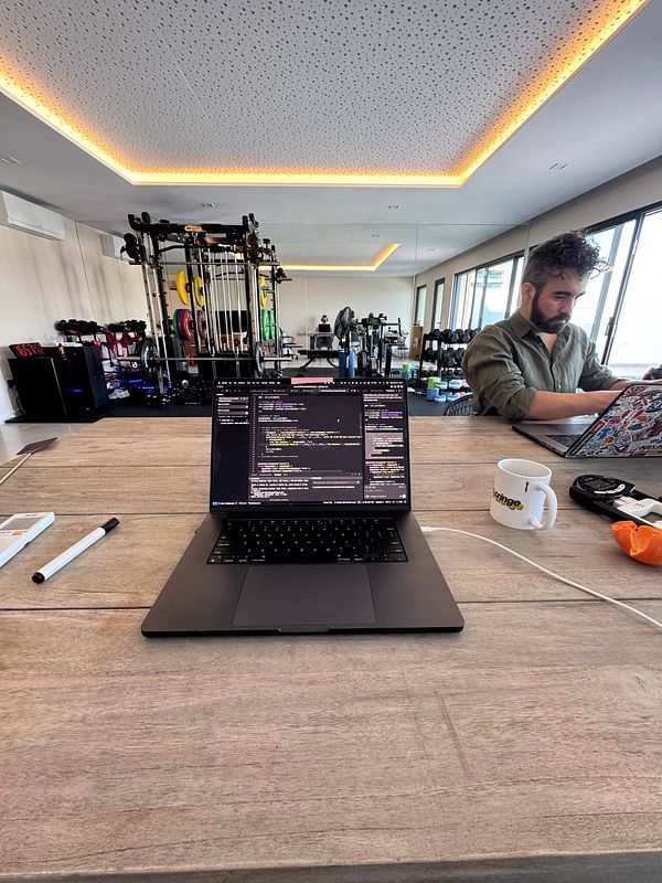 A coworking space featuring a laptop, workout equipment, and a person working.