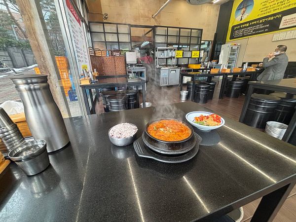 A close-up image of a Korean omelet dish served on a white plate with a spoon beside it, placed on a wooden table.