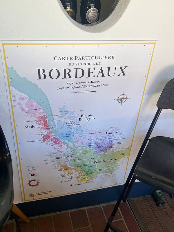 A detailed map of the Bordeaux wine region is displayed on a wall.