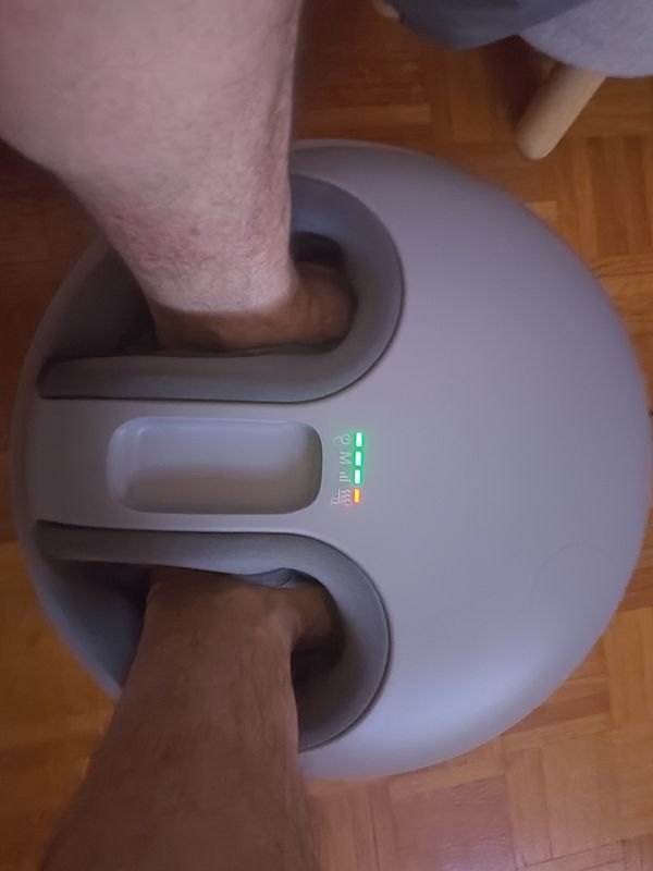 A person is using a foot massager with their feet inserted into the device.