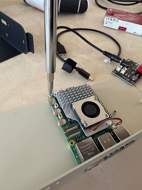 A Raspberry Pi is being assembled with a cooling fan and heatsink inside a vintage PC monitor casing.