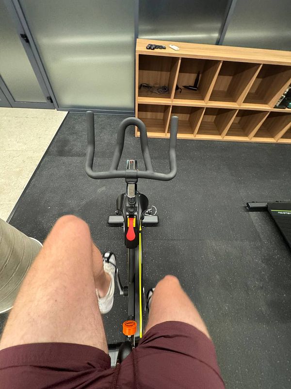 A person is seated on a stationary bike in a gym setting.