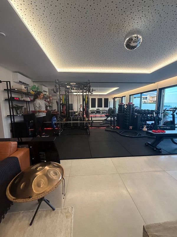 Modern home gym room with various workout equipment and a hanging musical instrument drum.