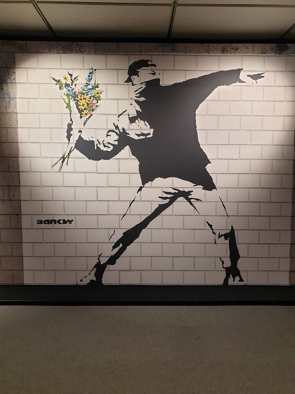 A striking mural of a figure throwing a bouquet of flowers against a brick wall.