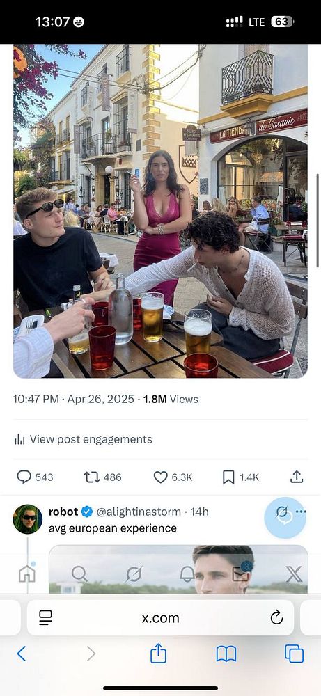A group of friends enjoys drinks at an outdoor café in Southern Europe, with a woman in a pink dress interacting with them.