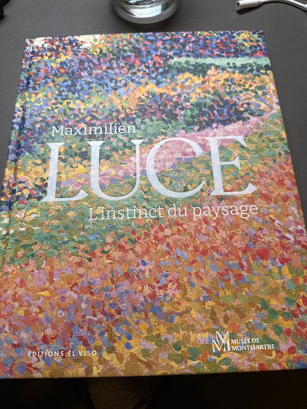 A book about Maximilien Luce is displayed on a table.