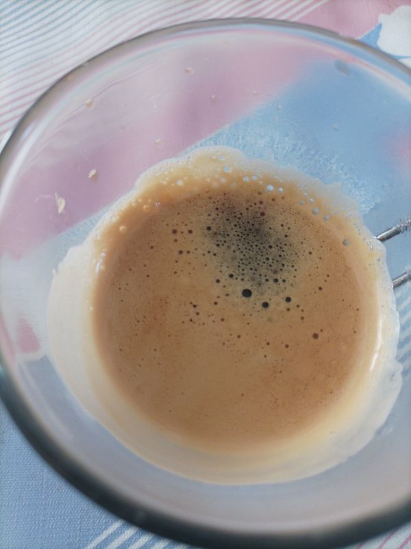A close-up view of a glass containing a freshly brewed espresso.