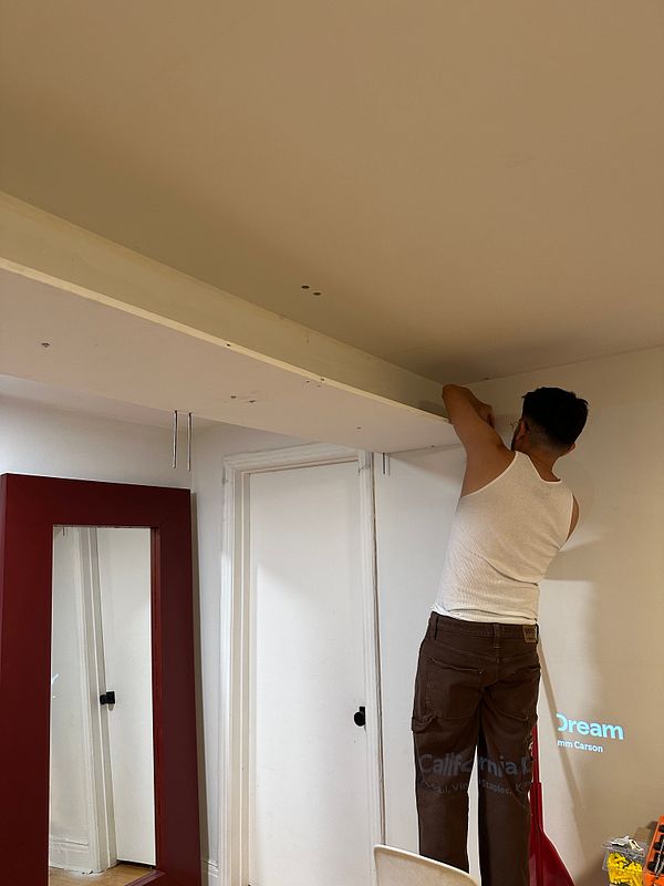 A person is installing shelves on a wall in a room.
