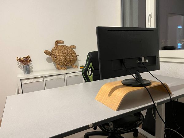 A newly arranged home office setup featuring a desk, monitor, and decorative elements.