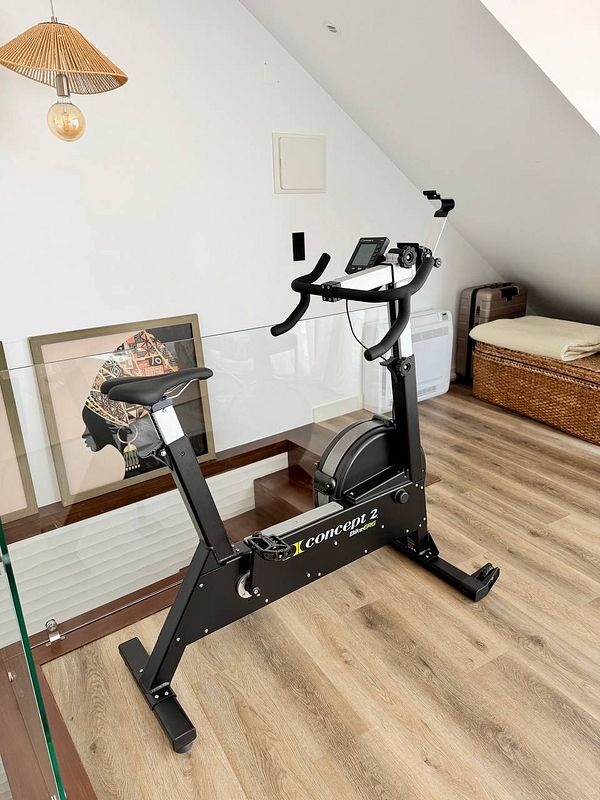 Concept2 BikeErg indoor bike with a mounted digital performance monitor on a wooden floor.