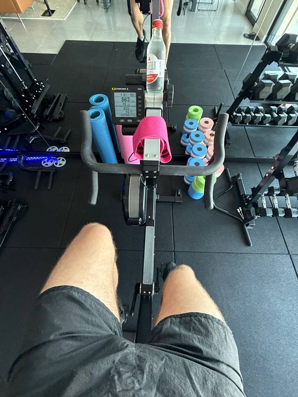 A person is exercising on a stationary bike in a gym setting.