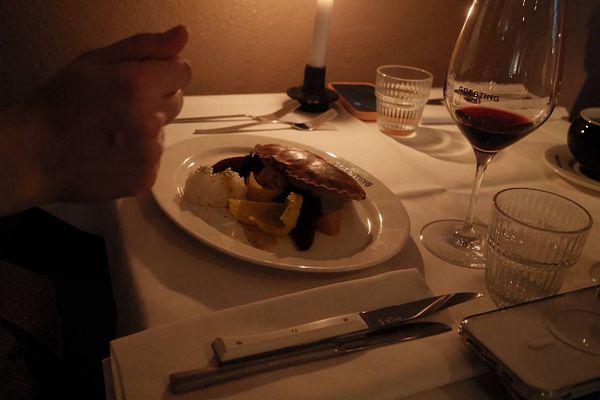 A beautifully set dinner table featuring a gourmet dish and a glass of red wine.