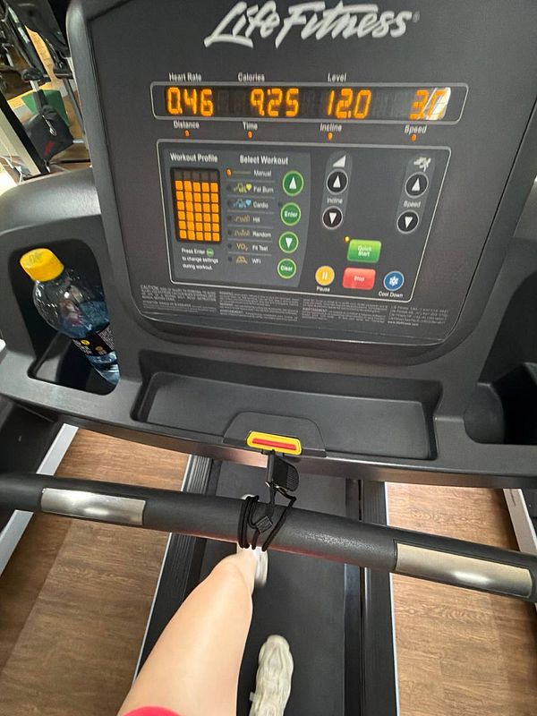 A woman performing a barbell squat exercise in a gym environment.