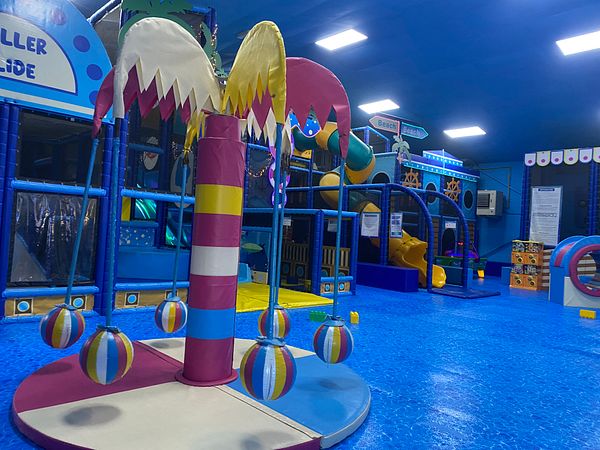 Indoor colorful children's play area with padded equipment and slides.