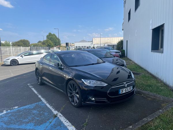 Side-by-side front views of a Tesla Model 3 and a Tesla Model S parked on a driveway.