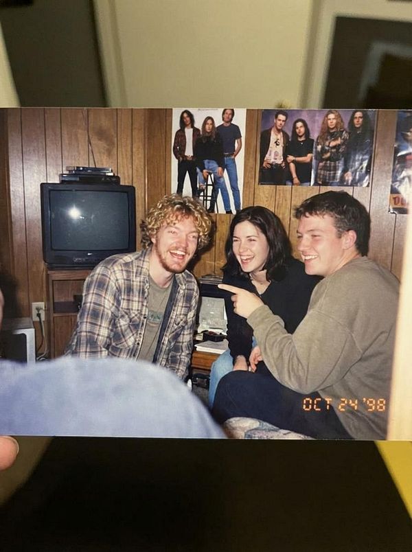 A nostalgic group photo featuring three friends laughing together in a cozy room.