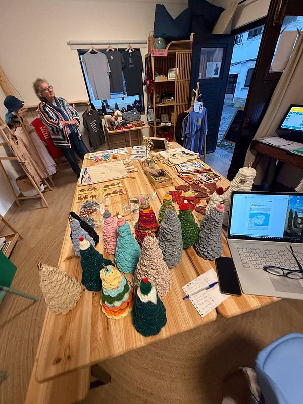 A cozy shop interior featuring handmade decorative trees and a person browsing.