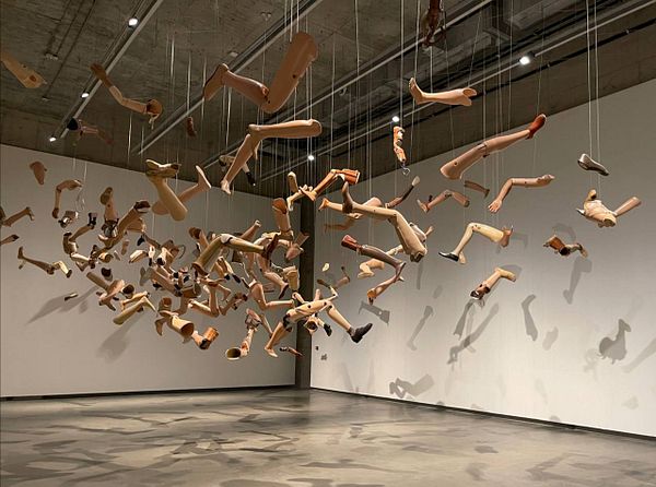 An art installation featuring numerous suspended mannequin limbs in a gallery space.