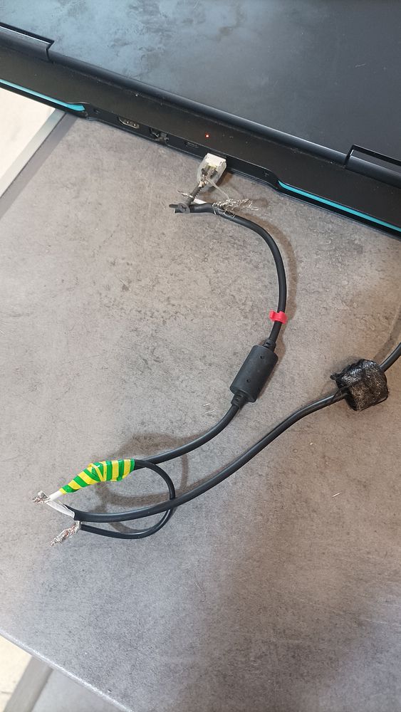 A makeshift repair of a broken laptop charger is displayed.