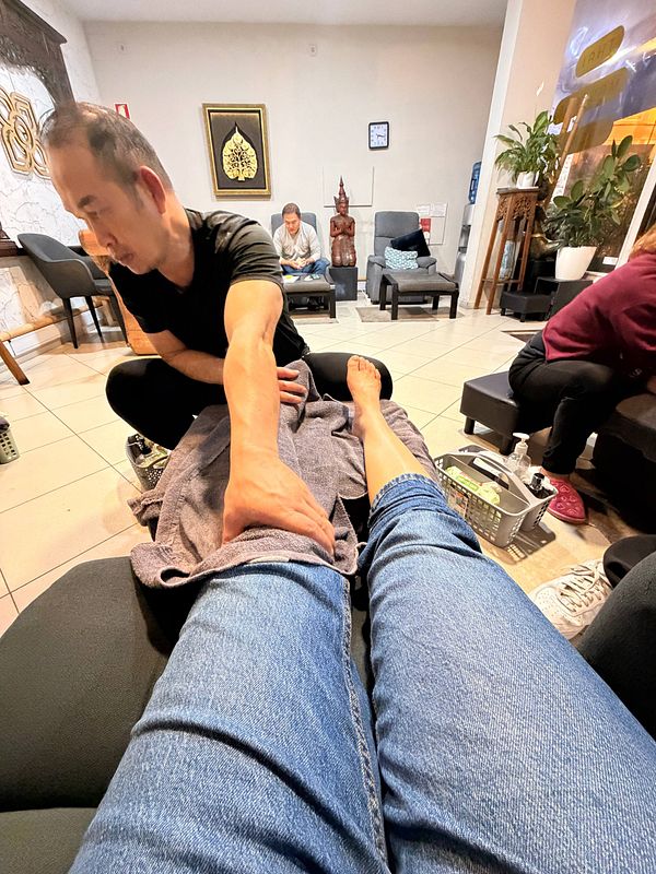 A peaceful outdoor setting with a woman receiving a foot massage in a garden.