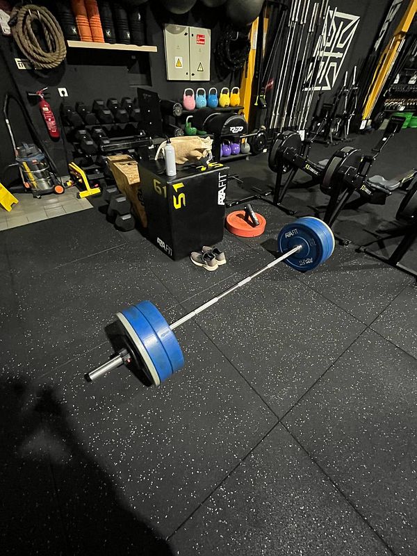 A gym setting featuring a barbell with weights and various fitness equipment.