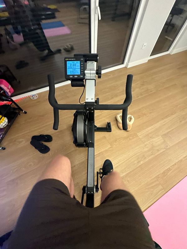 A person is seated on a rowing machine in a home gym setting.