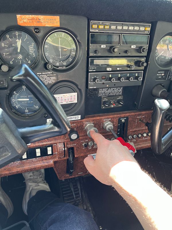 Pilot performing a preflight inspection on an airplane's wing and navigation antenna area.