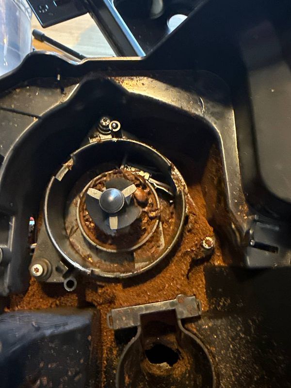 The image depicts the interior of a coffee machine that is heavily clogged with coffee grounds.