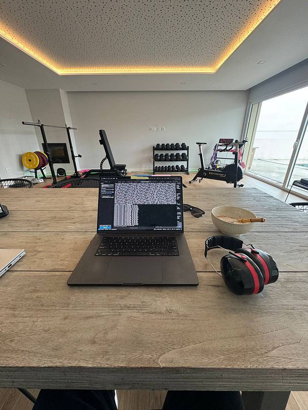 A modern coworking space featuring a laptop, gym equipment, and a bowl of food.