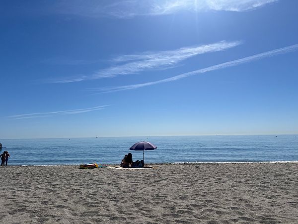 A serene beach scene featuring a family enjoying a sunny day by the water.
