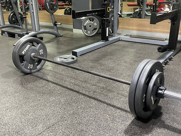 A barbell loaded with weights is positioned on a gym floor.