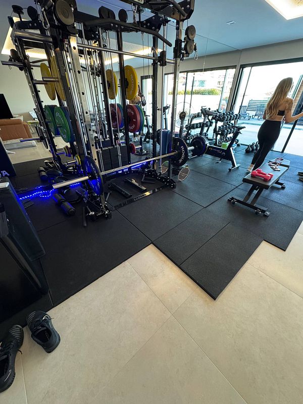A well-equipped home gym featuring various weightlifting equipment and a person preparing for a workout.